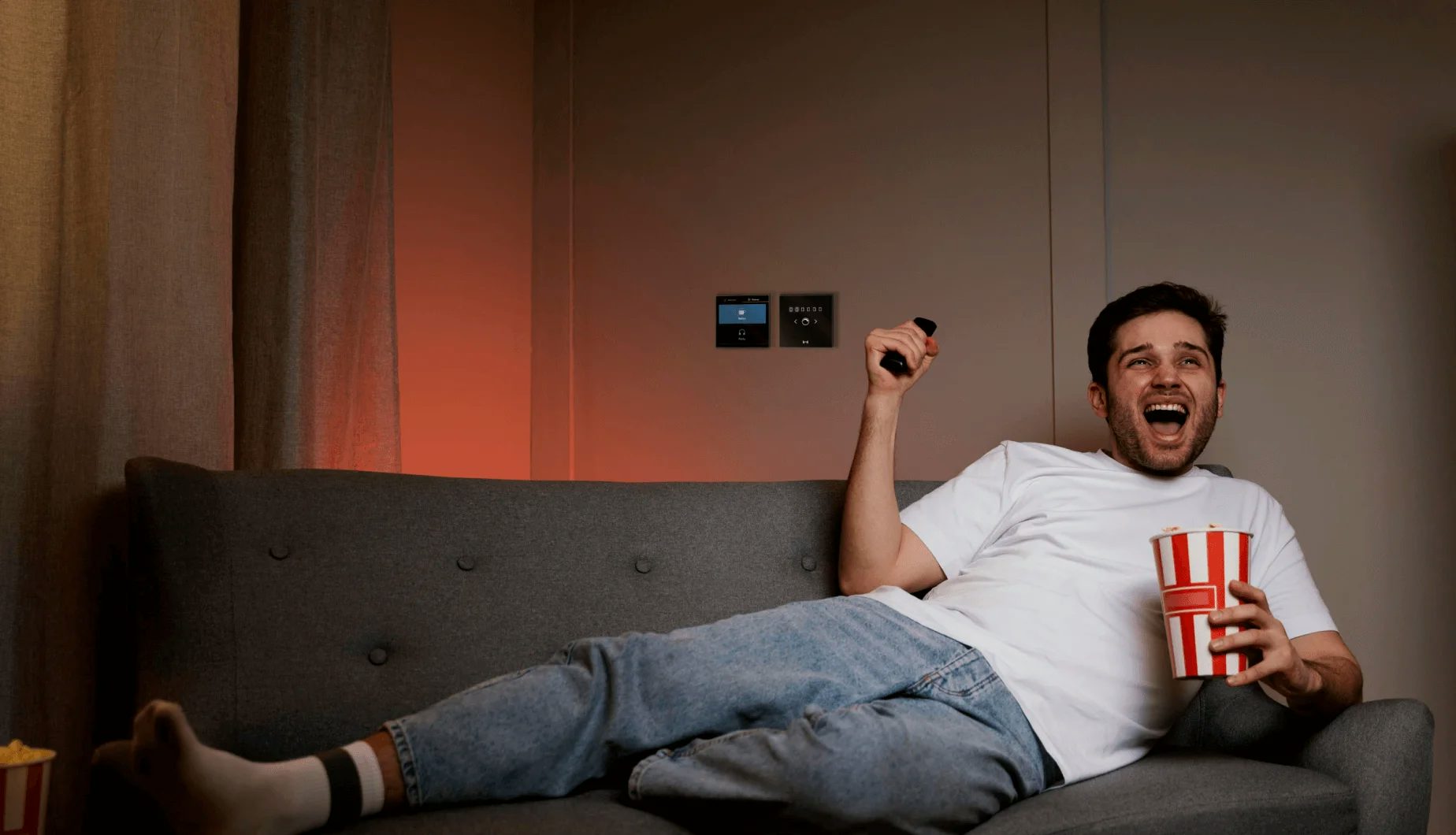 A man enjoying movie while having popcorns with MTronic Smart Dimmer and MTronic LCD Touch Panel installed and Movie scene activated